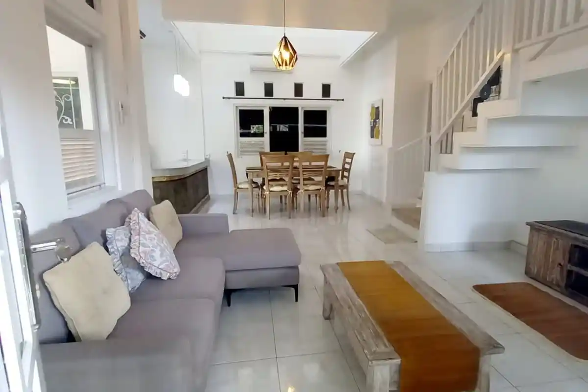 Bright villa living room with a grey sofa, dining table and white staircase