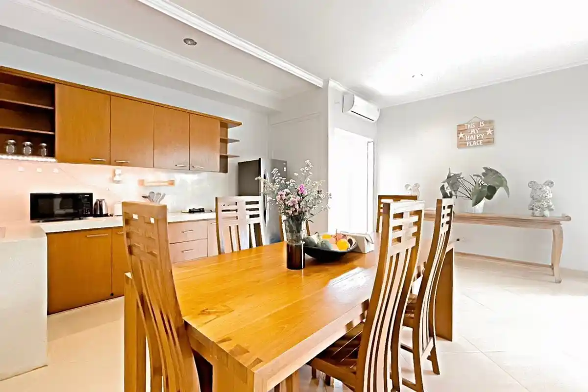 Wooden dining table beside a bright villa kitchen