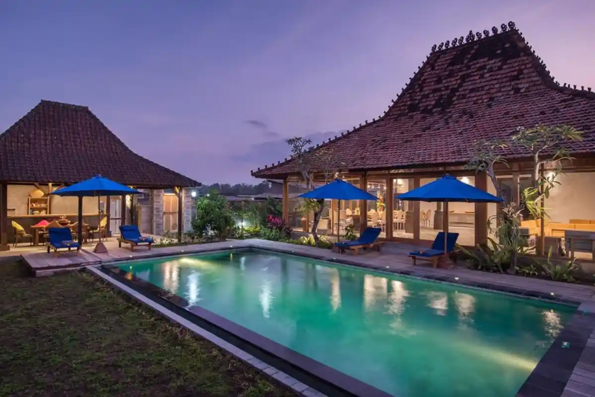 Villa roofs and an illuminated pool at dusk