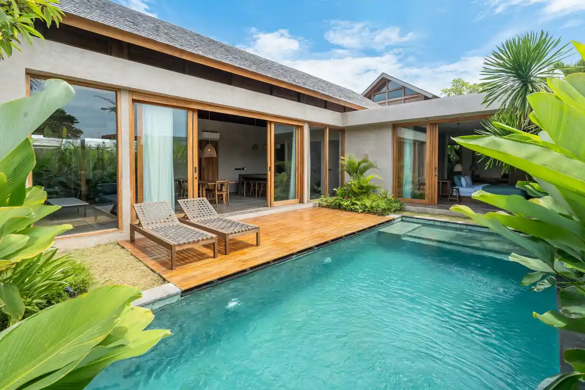 Tropical villa with sliding glass doors beside a turquoise pool