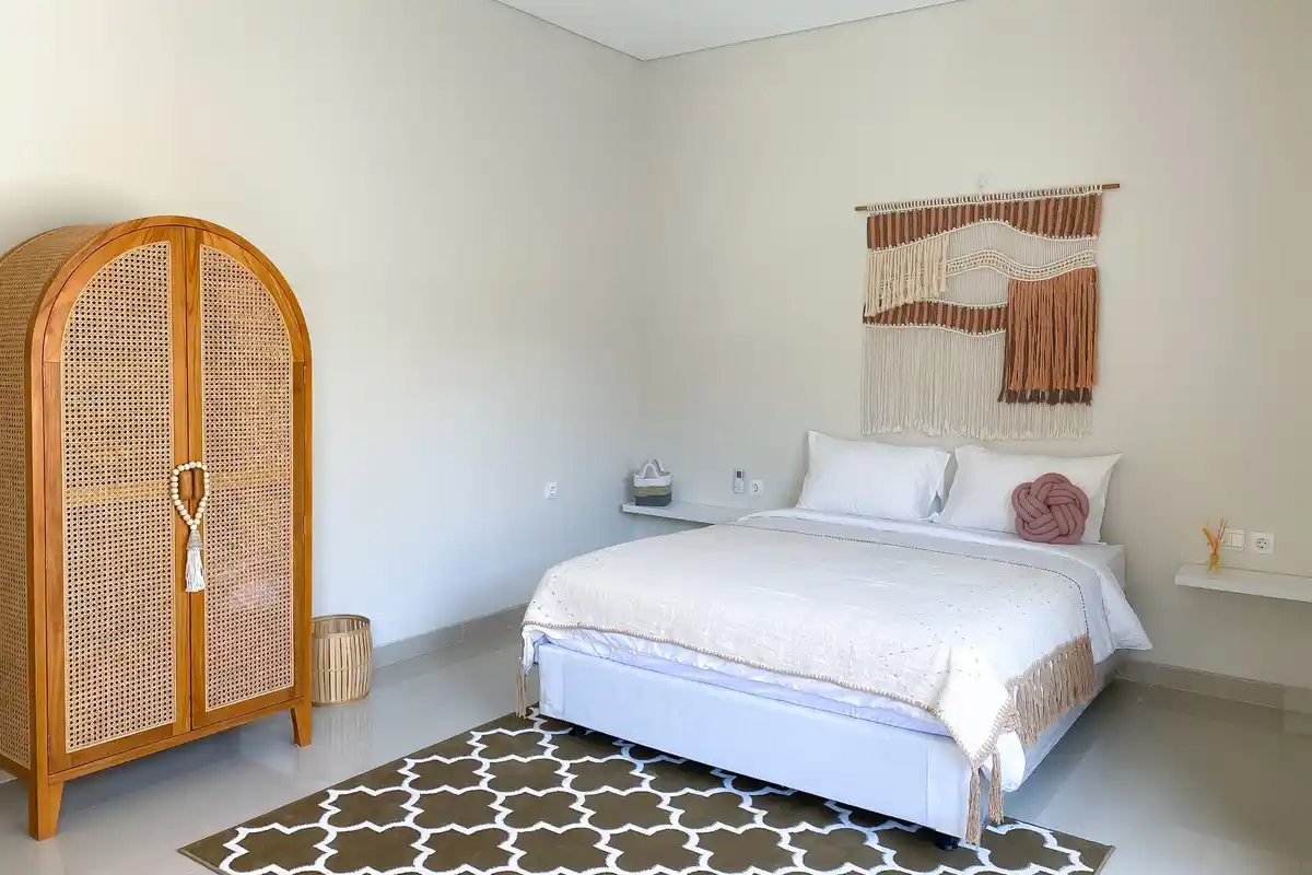 Bright bedroom with a rattan wardrobe and patterned rug